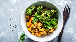 Vegan stew with chickpeas, sweet potato and kale in a white bowl.