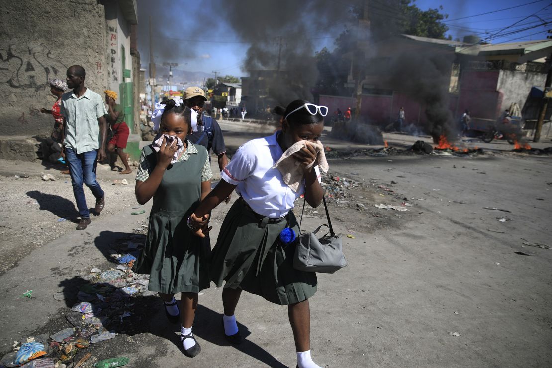 Students walk past a burning barricade that was set up by members of the police protesting bad police governance in Port-au-Prince, Haiti, Thursday, Jan. 26, 2023. (AP Photo/Odelyn Joseph)
