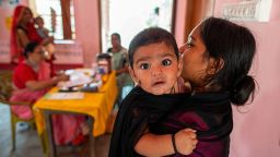 A mother carrying her young child waits for vaccination at a rural childcare center during a monthly child vaccination camp on June 19, in Brindaban village, Gopalganj, India.