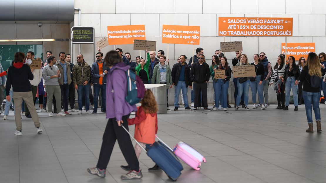 Travelers make their way to the departures area past cabin crew on a picket line, during pay-related strike action by EasyJet Plc, outside Lisbon Airport in Lisbon, Portugal, on Saturday, April 1, 2023. EasyJet cabin crew in Portugal have called a strike after an impasse in negotiations with the company.?Photographer: Zed Jameson/Bloomberg via Getty Images