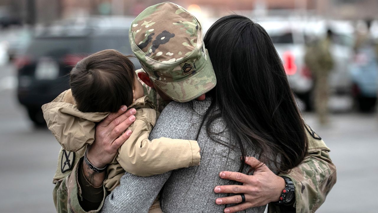 FORT DRUM, NEW YORK - DECEMBER 10: U.S. Army SSG. Tyler Laliberte embraces his family after returning from a 9-month deployment to Afghanistan on December 10, 2020 at Fort Drum, New York. The 10th Mountain Division soldiers who arrived this week are under orders to isolate with family at home or alone in barracks at Fort Drum, finishing their Covid-19 quarantine just before Christmas. The troops were replaced in Afghanistan by a smaller force, as the U.S. military continues to reduce troop levels Afghanistan. (Photo by John Moore/Getty Images)