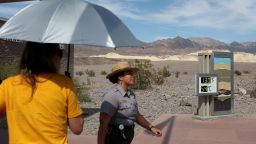 National Park Service Ranger Gia Ponce walks near a digital display of an unofficial heat reading at Furnace Creek Visitor Center during a heat wave in Death Valley National Park in Death Valley, California, on July 16, 2023. Tens of millions of Americans braced for more sweltering temperatures Sunday as brutal conditions threatened to break records due to a relentless heat dome that has baked parts of the country all week. By the afternoon of July 15, 2023, California's famous Death Valley, one of the hottest places on Earth, had reached a sizzling 124F (51C), with Sunday's peak predicted to soar as high as 129F (54C). Even overnight lows there could exceed 100F (38C). (Photo by Ronda Churchill / AFP) (Photo by RONDA CHURCHILL/AFP via Getty Images)
