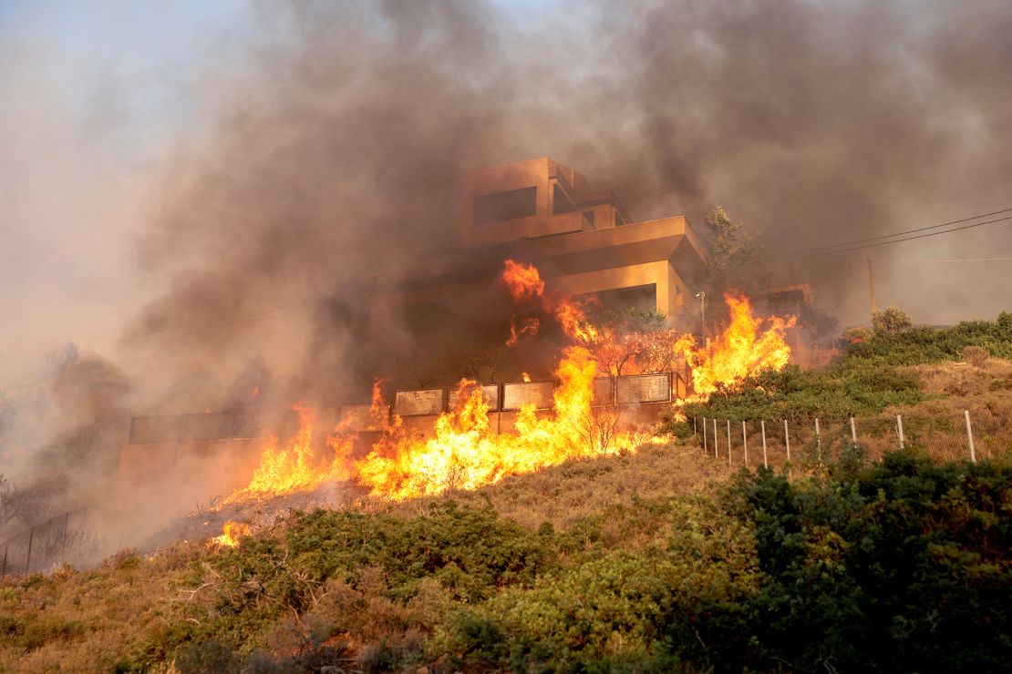 Flames engulf a house as a wildfire burns in Saronida near Athens on July 17, 2023. 