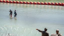 Texas Department of Public Safety (DPS) highway patrol troopers look over the Rio Grande as migrants walk by a string of buoys placed on the water along the Rio Grande border with Mexico in Eagle Pass, Texas, on July 15, 2023, to prevent illegal immigration entry to the US. The buoy installation is part of an operation Texas is pursuing to secure its borders, but activists and some legislators say Governor Greg Abbott is exceeding his authority. (Photo by SUZANNE CORDEIRO / AFP) (Photo by SUZANNE CORDEIRO/AFP via Getty Images)