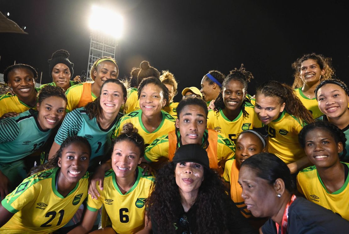 Cedella Marley (C bottom) poses with Jamaica Women's football team 'Reggae Girlz'  after the friendly football match Jamaica vs Panama at the National Stadium in Kingston, Jamaica on May 19, 2019. - In Jamaica, the spirit of Bob Marley is inescapable: it permeates the Caribbean island nation, even its football pitches -- a sign of the late reggae legend's passion for the sport. After Marley's death, his children picked up the torch -- and the country's women's team, who have qualified for their first-ever World Cup this summer in France, owe a lot to the musician's daughter Cedella. (Photo by Angela Weiss / AFP)        (Photo credit should read ANGELA WEISS/AFP via Getty Images)