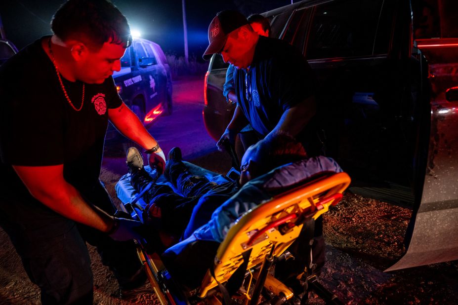 Israel Sanchez, left, and Alfonso Garcia carry a person onto a stretcher in Eagle Pass, Texas, on July 18. The person, who was suffering from dehydration, fell sick after he and his mother were found with a group of migrants who recently crossed the Rio Grande into the United States.