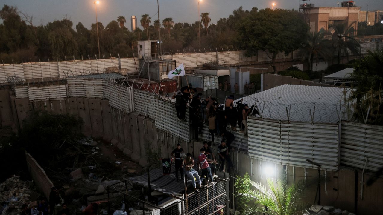 Protesters climb a fence as they gather near the Swedish embassy in Baghdad, Iraq on July 20, 2023.