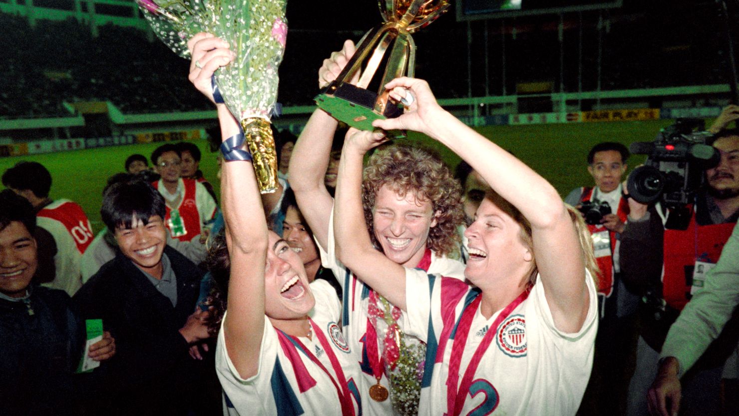 Michelle Akers-Stahl (C) who scored two goals for the US to win the first FIFA World Championship for Women's Football on November 30, 1991, holds the trophy together with teammates Julie Foudy (L) and Carin Jennings (R). The US won the championship by beating Norway 2-1. The FIFA Women's World Cup is recognized as the most important International competition in women's football and is played amongst women's national football teams of the member states of FIFA. Contested every four years, the first Women's World Cup tournament, named the Women's World Championship, was held in 1991, sixty-one years after the men's first FIFA World Cup tournament in 1930AFP PHOTO TOMMY CHENG (Photo credit should read TOMMY CHENG/AFP via Getty Images)