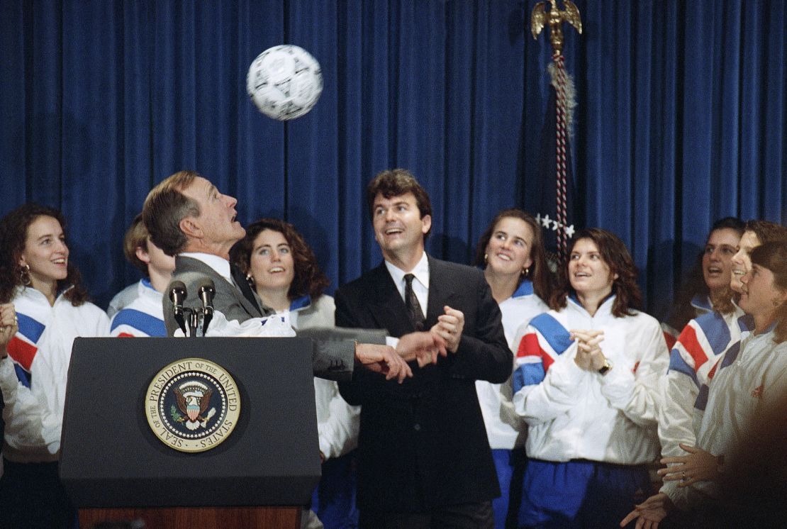 President George Bush heads a soccer ball while meeting the 1991 Women's World Cup soccer champs, Jan. 23, 1992 in Washington. Anson Dorrance, coach of the team looks on at right. (AP Photo/Barry Thumma)