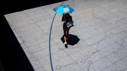 A woman uses an umbrella to shade herself from the hot sun, while leaving Cathedral of Our Lady of the Angels, in downtown Los Angeles, CA, Tuesday, July 18, 2023. 