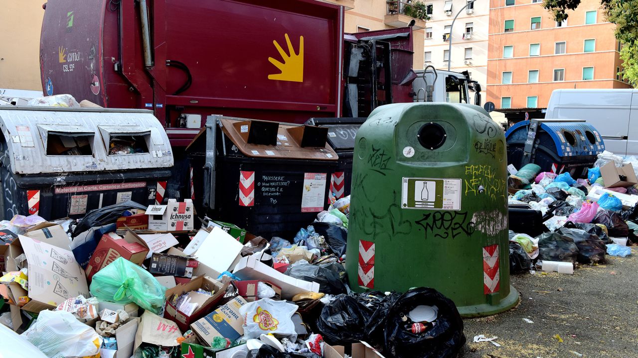 A collection truck in front of huge piles of rubbish in Rome, pictured on June 28, 2023 