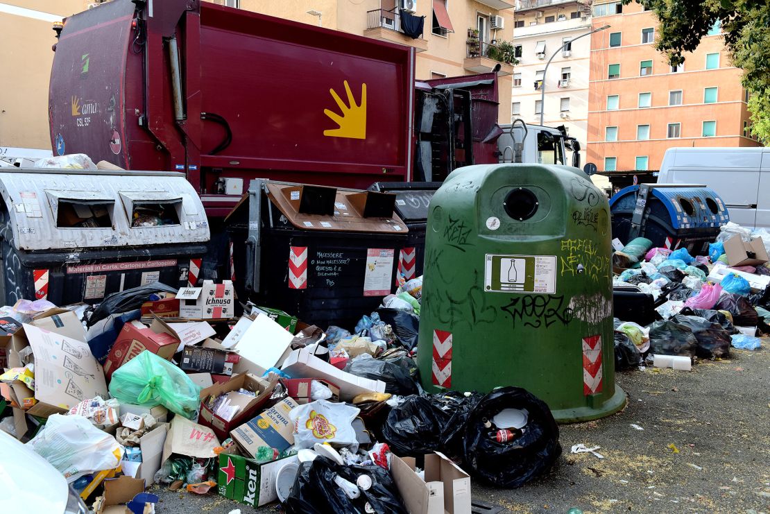 A collection truck in front of huge piles of rubbish in Rome, pictured on June 28, 2023 