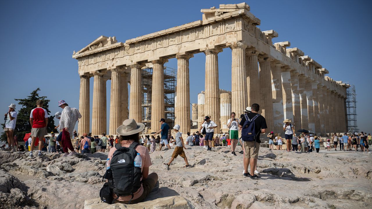 I turisti camminano intorno alla collina dell'Acropoli di Atene il 14 luglio 2023.