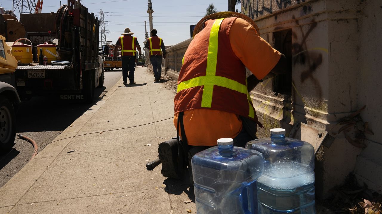 Electricians with IBEW Local 11 pull out an old copper cable line under excessive heat from the old Cesar Chavez Avenue Viaduct in Los Angeles, Thursday, July 13, 2023.