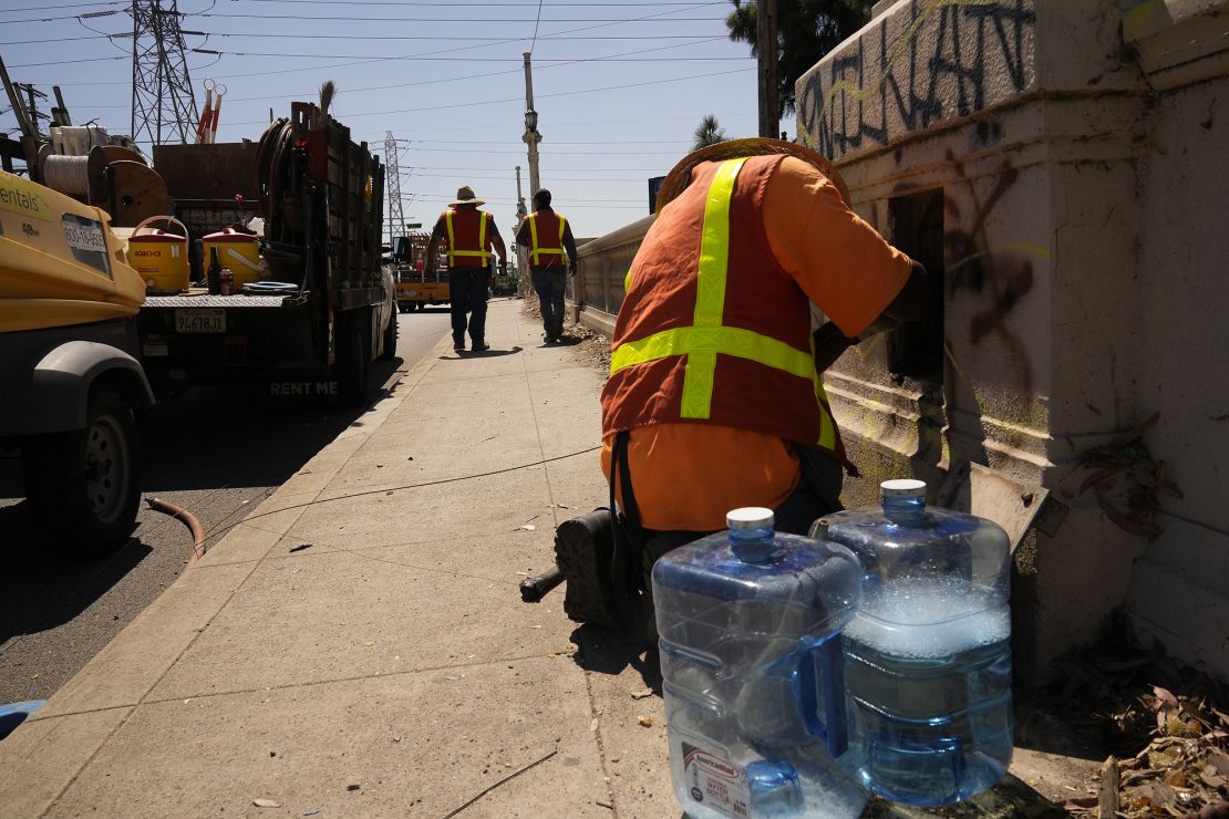 Electricians with IBEW Local 11 pull out an old copper cable line under excessive heat from the old Cesar Chavez Avenue Viaduct in Los Angeles, Thursday, July 13, 2023. 