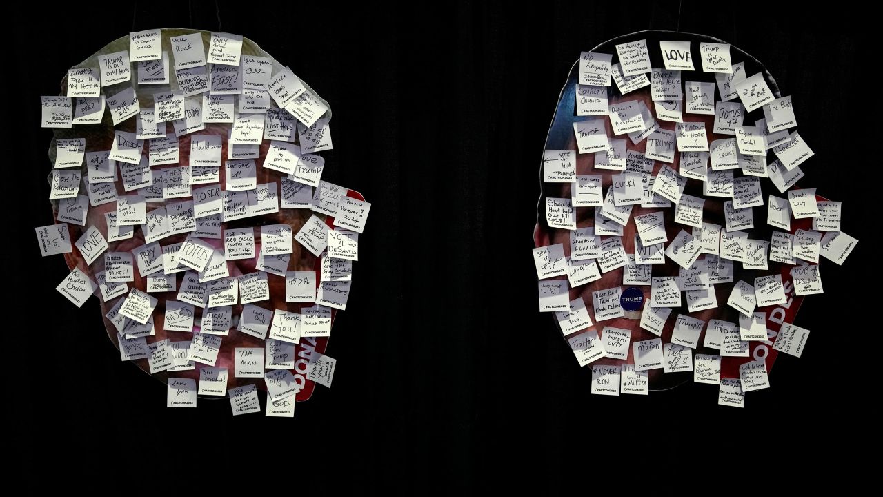 Images of Trump, left, and Florida Gov. Ron DeSantis, right, covered with messages written on sticky notes at the Turning Point Action conference.