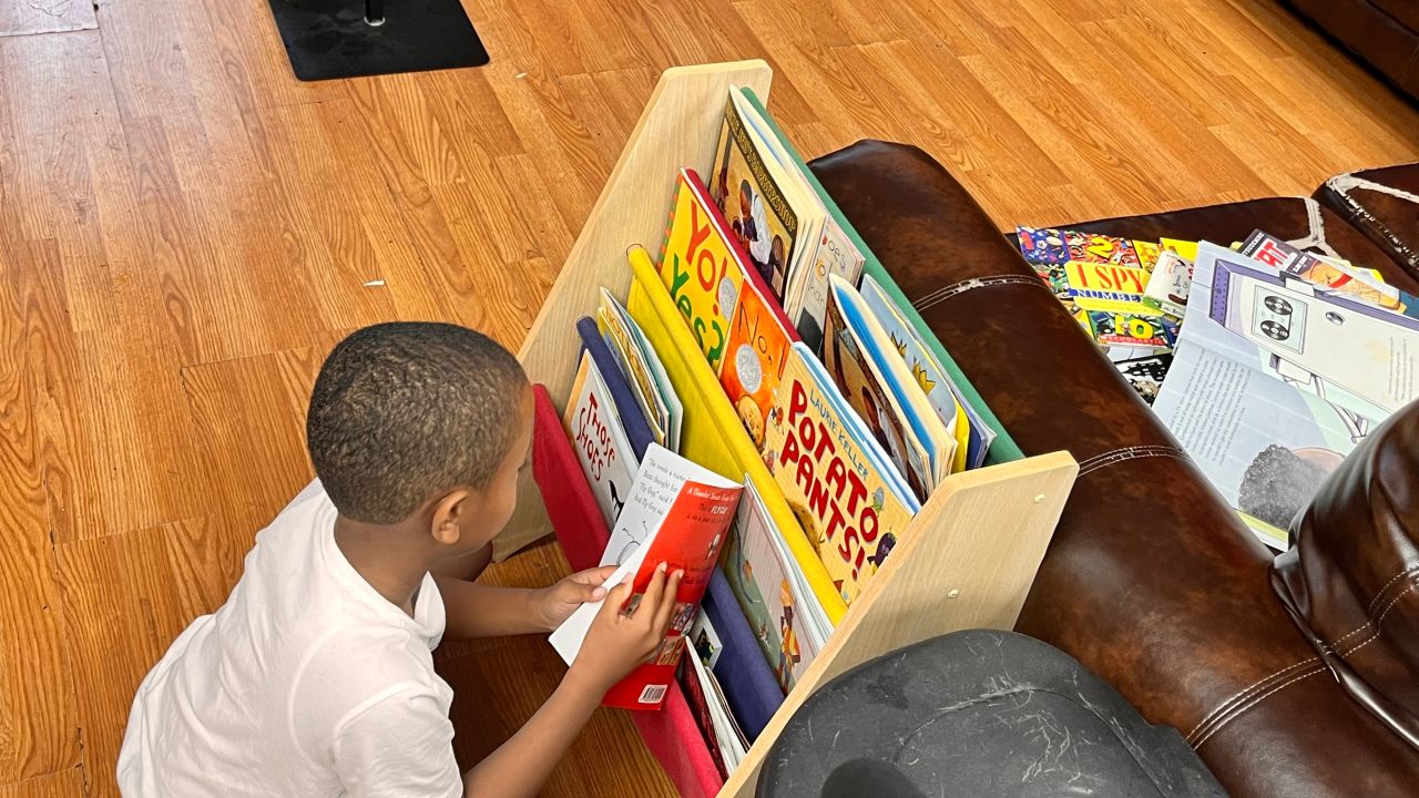A child selects a book from a barbershop shelf as part of CNN Hero Alvin Irby's program.