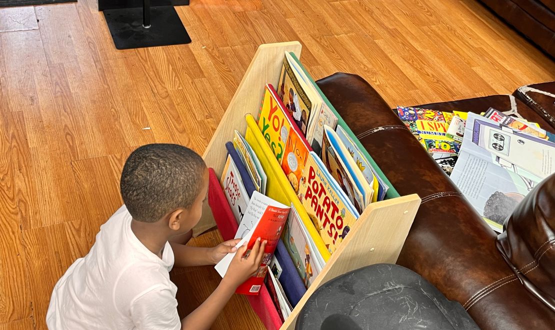 A child selects a book from a barbershop shelf as part of CNN Hero Alvin Irby's program.