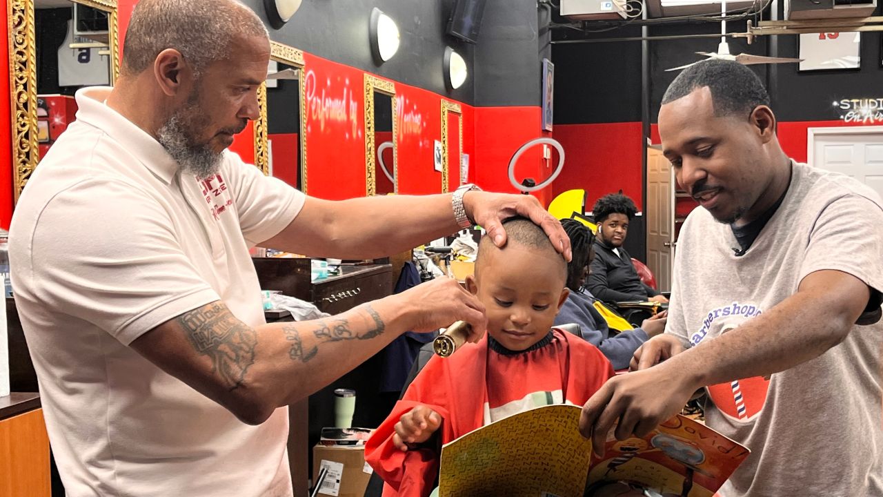 CNN Hero Alvin Irby, right, reads with a young boy during his haircut at Mike Murphy's barbershop in Philadelphia.