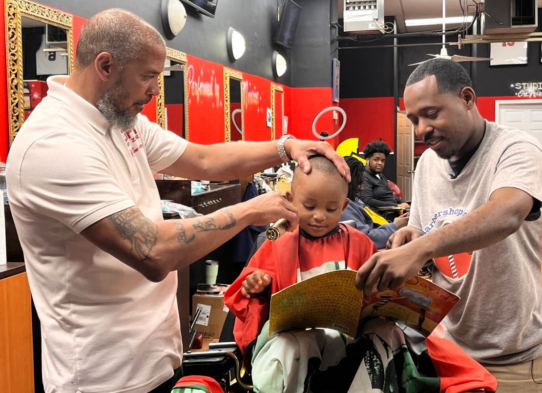 CNN Hero Alvin Irby, right, reads with a young boy during his haircut at Mike Murphy's barbershop in Philadelphia.