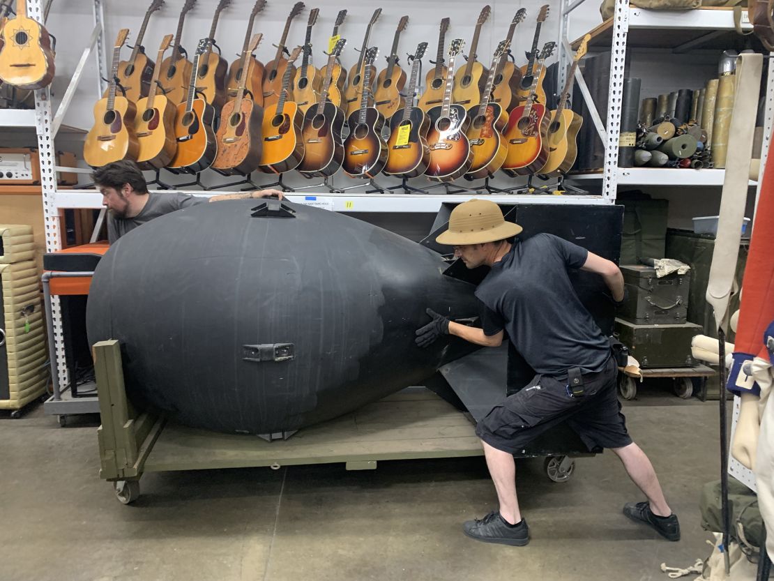 History for Hire staffers Remy De La Mora (in front) and Patrick Gallagher (in back) move a prop atomic bomb that was used on set during the filming of "Oppenheimer." They're moving it outside the warehouse to show during the Crewlateral Yard Sale. 