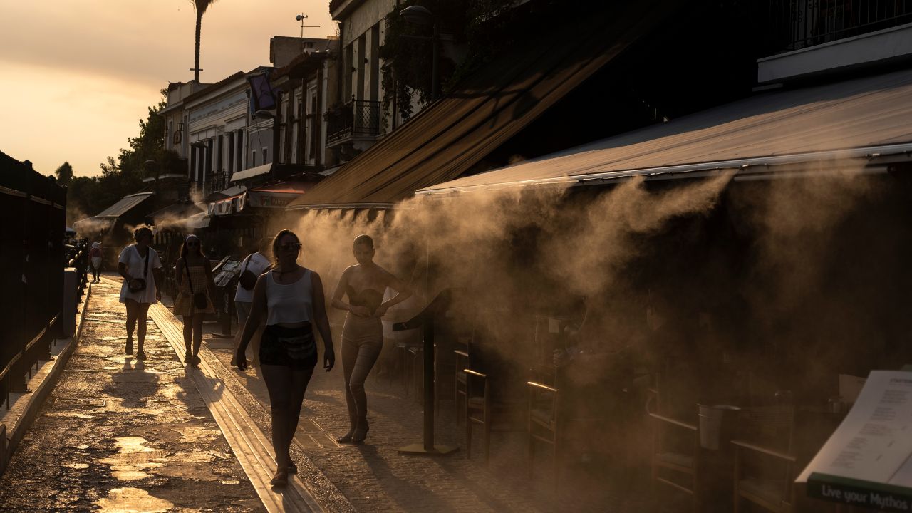 People walk next to a mist machine to cool down, in the Monastiraki district of Athens, on Thursda.