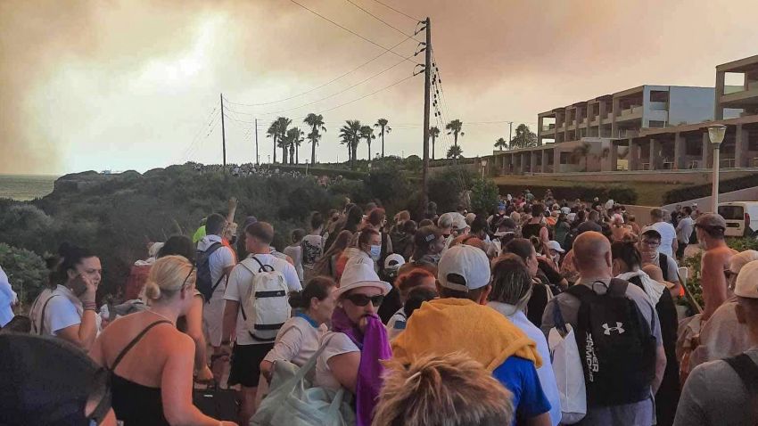 Tourists are evacuated from hotels during a wildfire on the Greek island of Rhodes on July 22, 2023. Three coastguard boats were leading more than 20 vessels in an emergency evacuation effort to rescue people from the Greek island, where fire has been raging out of control for five days. 