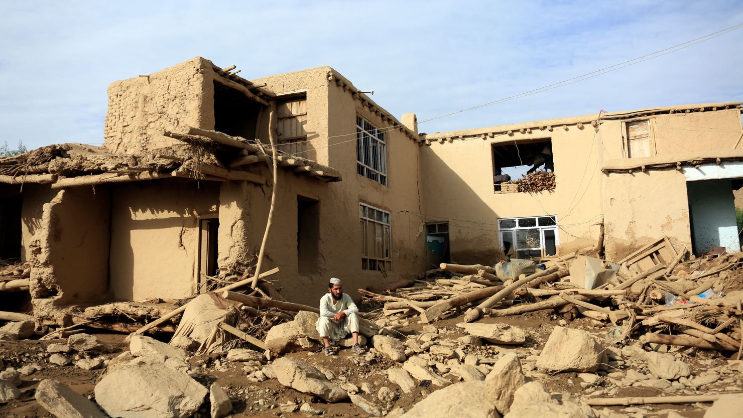 A man sits near his damaged house after heavy flooding in the Maidan Wardak province in central Afghanistan, Sunday, July 23, 2023. 