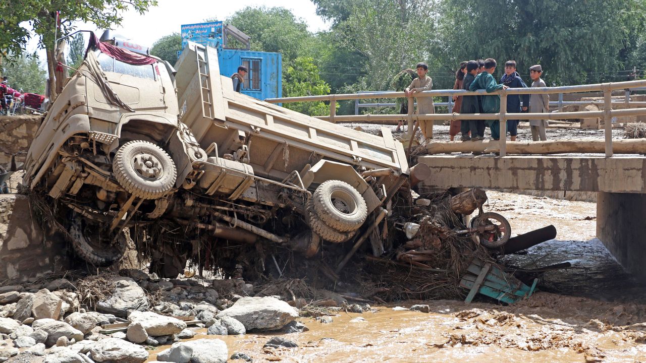 Afghan boys look at a truck that was damaged in flash floods in Maidan Wardak province on July 23, 2023.