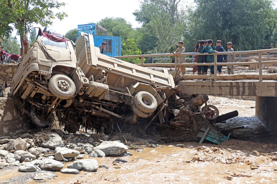 Afghan boys look at a truck that was damaged in flash floods in Maidan Wardak province on July 23, 2023. 
