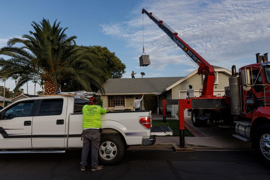 Roberto Guerrero, left, and his son Jose work in the early morning to install a new air conditioner at a home in Phoenix on July 18. Guerrero is part of perhaps the most essential workforce in town: AC repair techs. "If they need us, we go," he said of the long work hours.