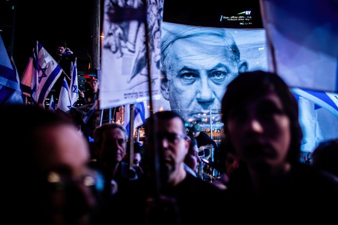 Protesters stand under a photo of Netanyahu during a demonstration in Tel Aviv, Israel, in April 2023. For months, Israelis have been taking to the streets to <a href="index.php?page=&url=http%3A%2F%2Fwww.cnn.com%2F2023%2F07%2F24%2Fmiddleeast%2Fgallery%2Fisrael-judicial-reform-july-protests%2Findex.html" target="_blank">protest proposed changes to the country's legal system</a>.