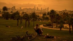 A person sits in Delores Park as smoke and fog hang over the skyline in San Francisco, California, on Wednesday, Sept. 9, 2020.