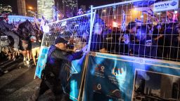 An Israeli riot policeman stands behind a metal fence being shoved by demonstrators during a protest rally against the Israeli government's judicial overhaul plan in Tel Aviv on Monday. 