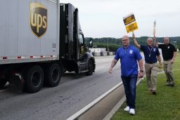 A UPS truck drives by as Teamsters President Sean O'Brien, left, and union members at a rally Friday in Atlanta.
