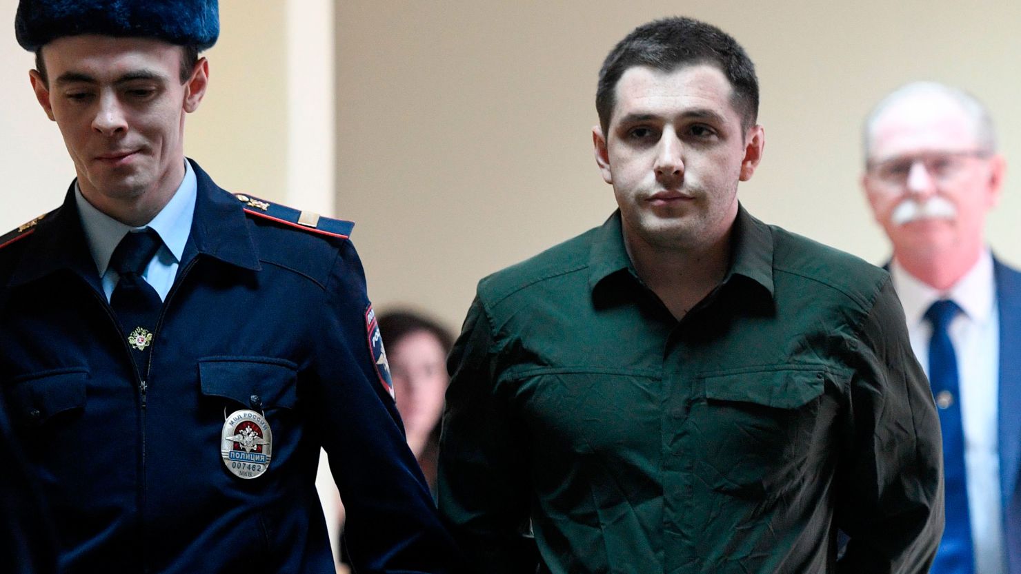 Police officers escort US ex-marine Trevor Reed, charged with attacking police, into a courtroom prior to a hearing in Moscow on March 11, 2020.