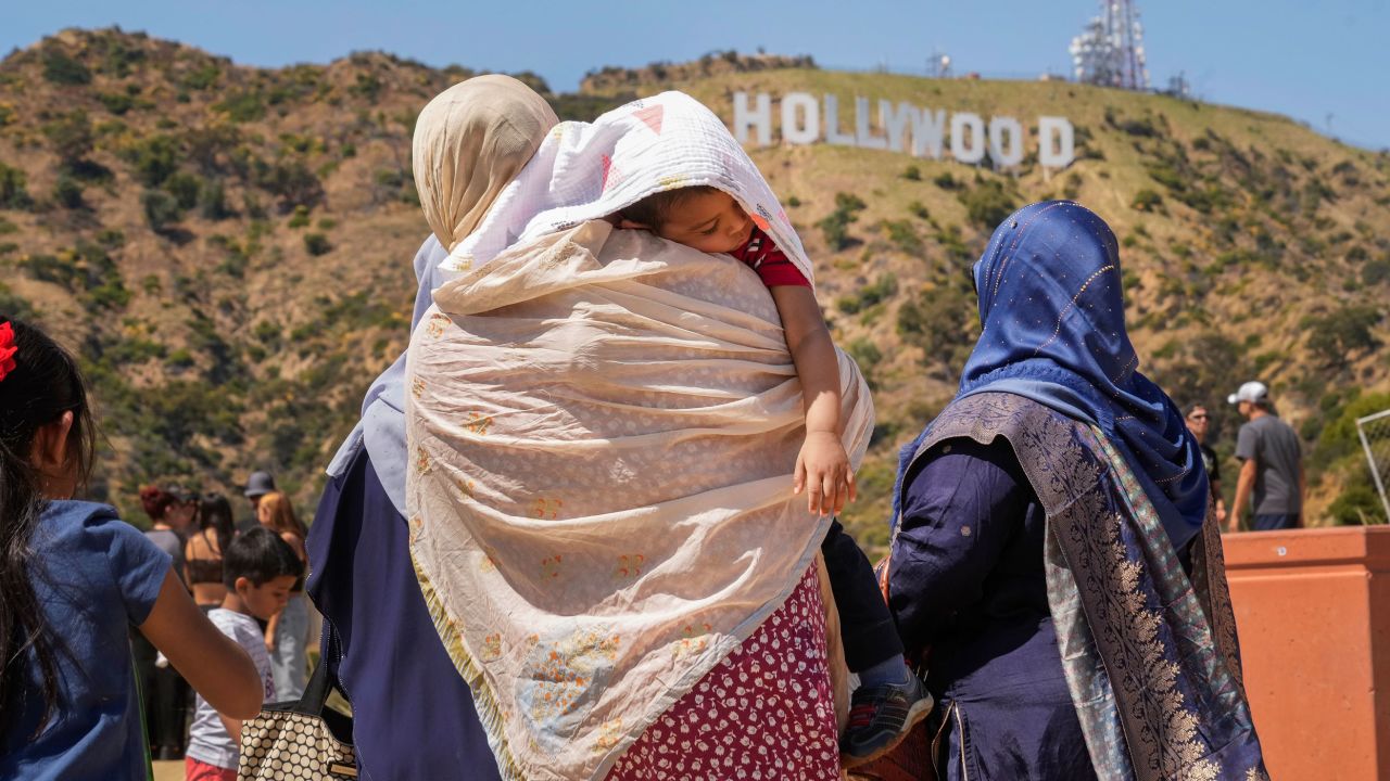 Tourists protect a sleeping child from the sun as they visit the Hollywood sign landmark in Los Angeles on July 12.