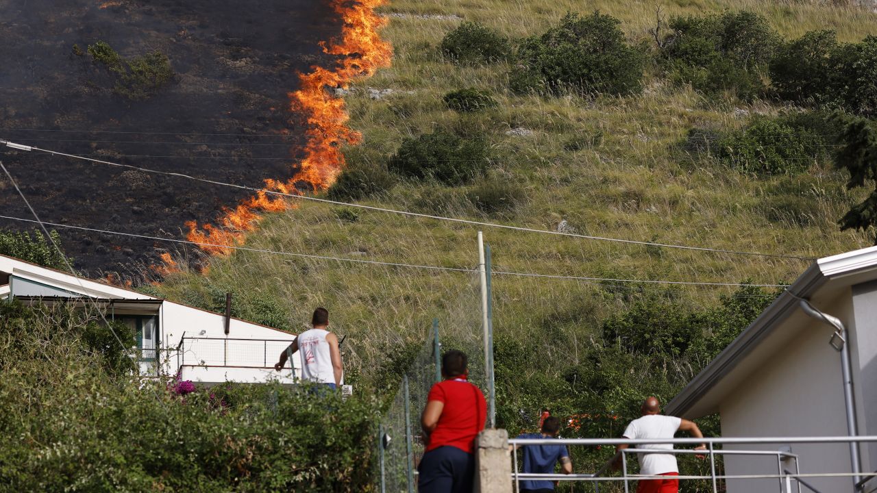 Residents watch a fire burning in Capaci, near Palermo, in Sicily, southern Italy, Wednesday, July 26, 2023. 
