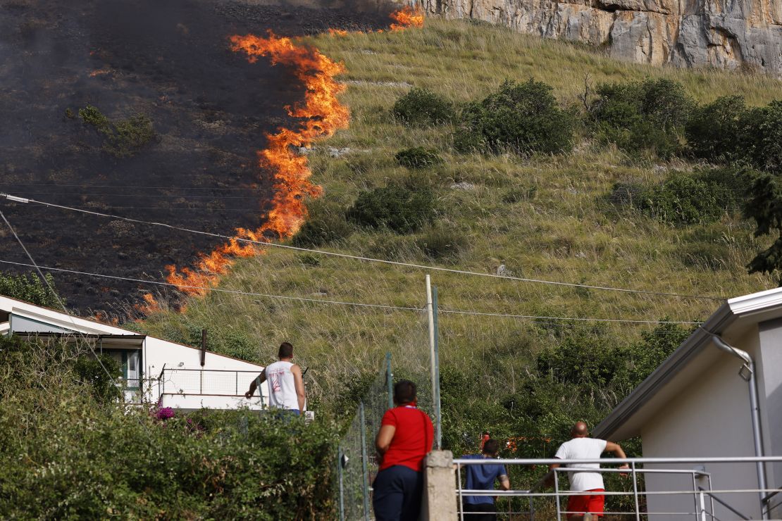 Residents watch a fire burning in Capaci, near Palermo, in Sicily, southern Italy, on July 26. 
