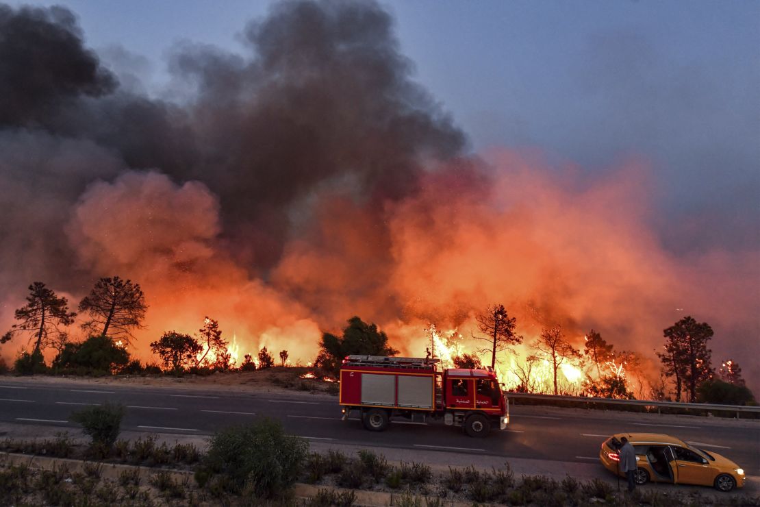 A fire truck moves along a road as a forest fire rages near the town of Melloula in northwestern Tunisia on July 24.