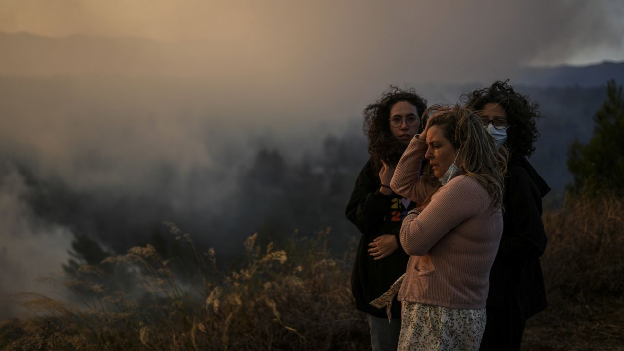 Villagers watch a wildfire as it approaches Zambujeiro village in Cascais, Portugal, on July 25.