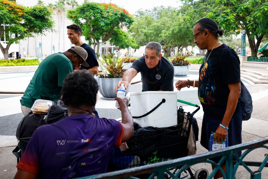 Representatives of the Miami-Dade County Homeless Trust distribute shelter information and bottles of water to people in Miami on July 25.