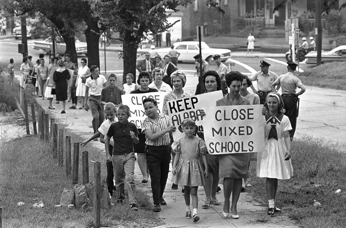 Mothers carrying protest signs accompany their children to Graymont Elementary School in Birmingham, Ala., which was opened on an integrated basis, Sept. 4, 1963. (AP Photo)