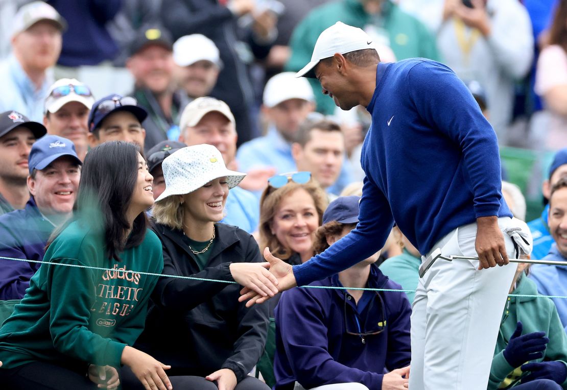 AUGUSTA, GEORGIA - APRIL 03: Tiger Woods of The United States says hello to Rose Zhang (front left green top) the winner of the Augusta National Women's Amateur and a friend behind the tee on the 12th hole during a practice round prior to the 2023 Masters Tournament at Augusta National Golf Club on April 03, 2023 in Augusta, Georgia. (Photo by David Cannon/Getty Images)