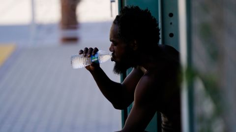 A person drinks a bottle of water in the shade as temperatures are expected to hit 119-degrees (48.3 Celsius) Thursday, July 20, 2023, in Phoenix. (AP Photo/Ross D. Franklin)