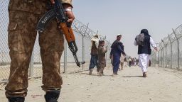  Пакистански войник стои на стража, докато блокираните афганистански граждани се връщат в Афганистан на пакистанско-афганистанския граничен контролно-пропускателен пункт в Чаман на 15 август 2021 г. class=