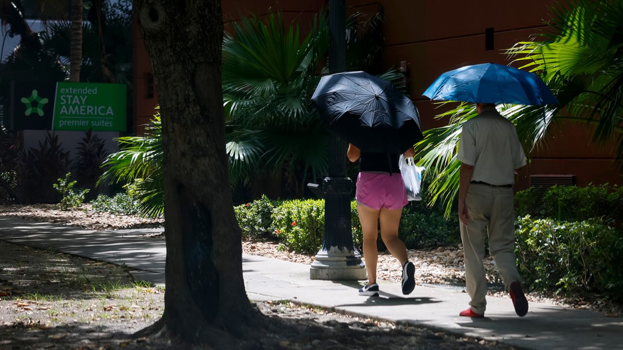 Pedestrians carry umbrellas during a heat wave in Miami, Florida,on July 25. 