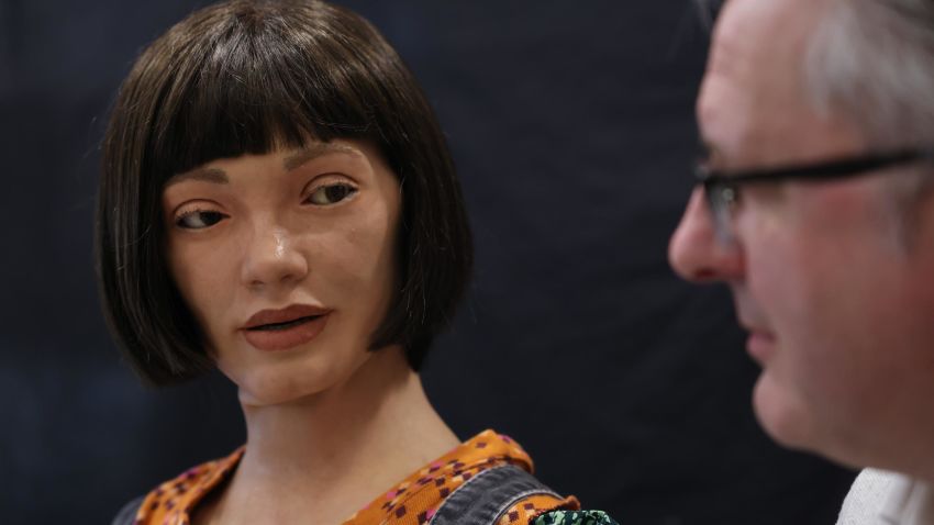 LONDON, ENGLAND - APRIL 04: Ai-Da Robot, an ultra-realistic humanoid robot artist, looks towards Aidan Meller during a press call at The British Library on April 4, 2022 in London, England. Ai-Da will open her solo exhibition LEAPING INTO THE METAVERSE at the Venice Biennale this year curated by Meller. (Photo by Hollie Adams/Getty Images)