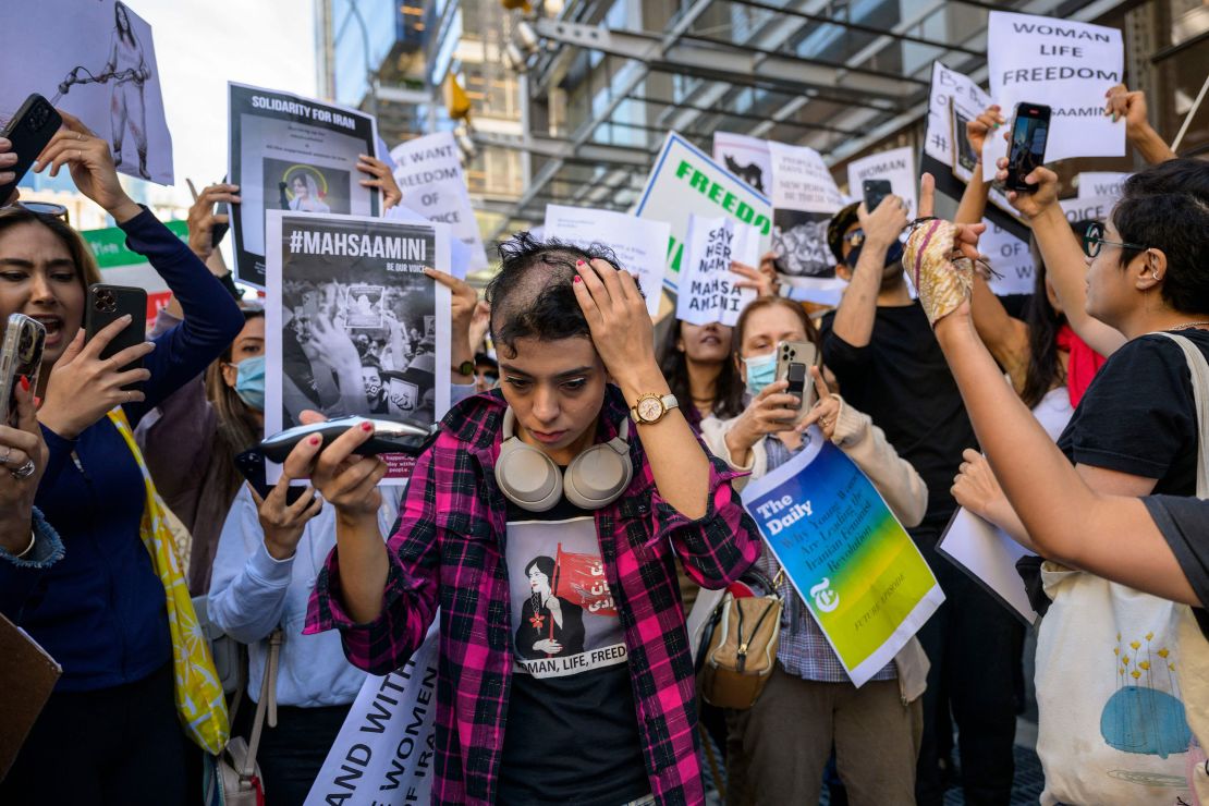 TOPSHOT - Activist Forouzan Farahani shaves her head in protest over the death of Mahsa Amini in Iran outside The New York Times building in New York City on September 27, 2022. - More than 75 people have been killed in the Iranian authorities' crackdown against unrest sparked by the death of Kurdish woman Mahsa Amini in morality police custody, a rights group said on September 26. (Photo by ANGELA WEISS / AFP) (Photo by ANGELA WEISS/AFP via Getty Images)