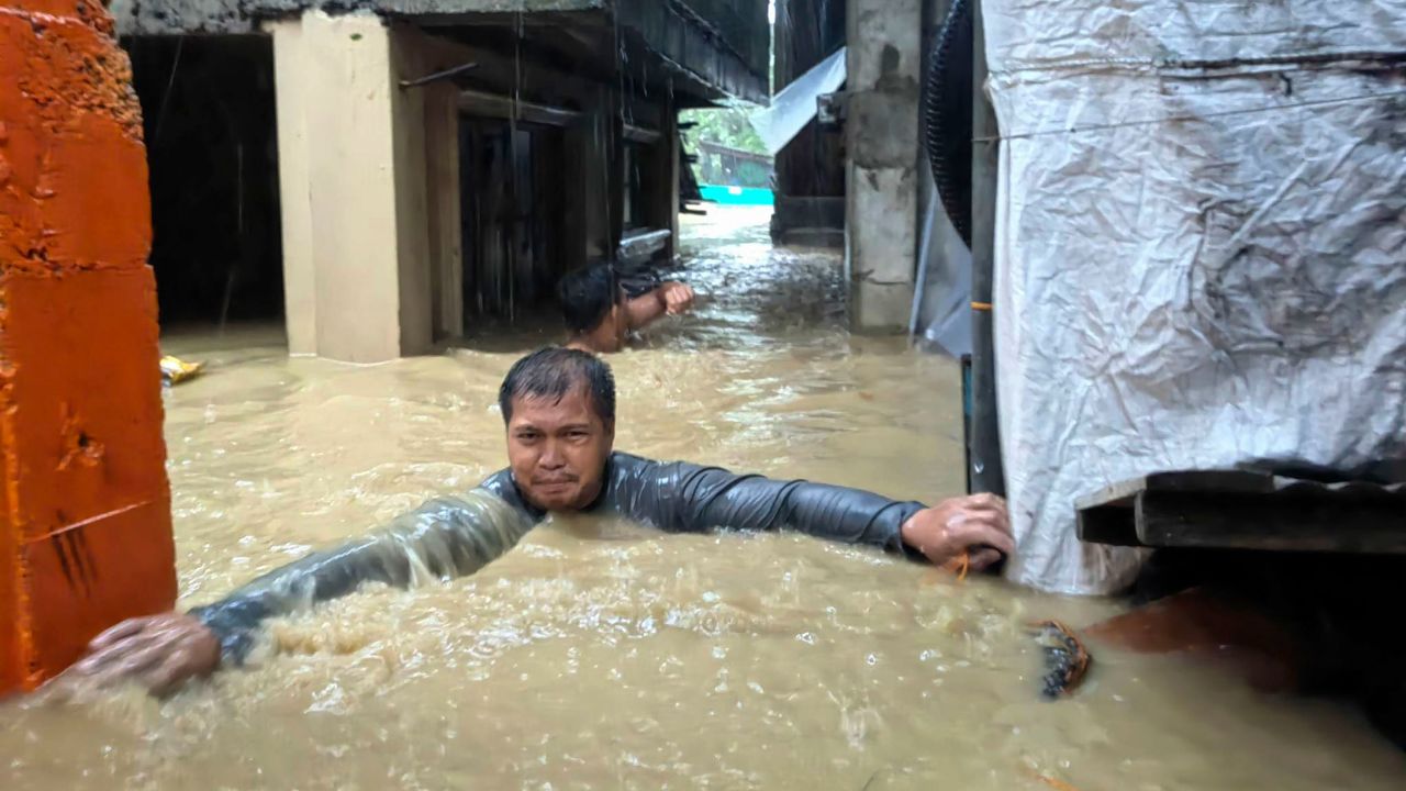  Човек преговаря с наводнения, дълбоки до шия, в град Лаоаг, провинция Илокос Норте, северни Филипини. class=